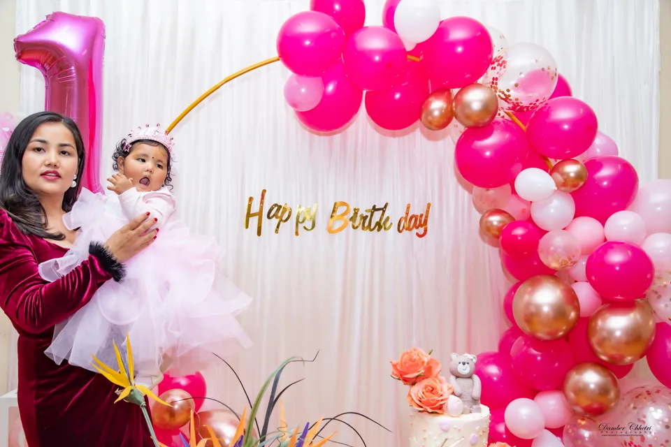 A mother holding her toddler at a first birthday celebration