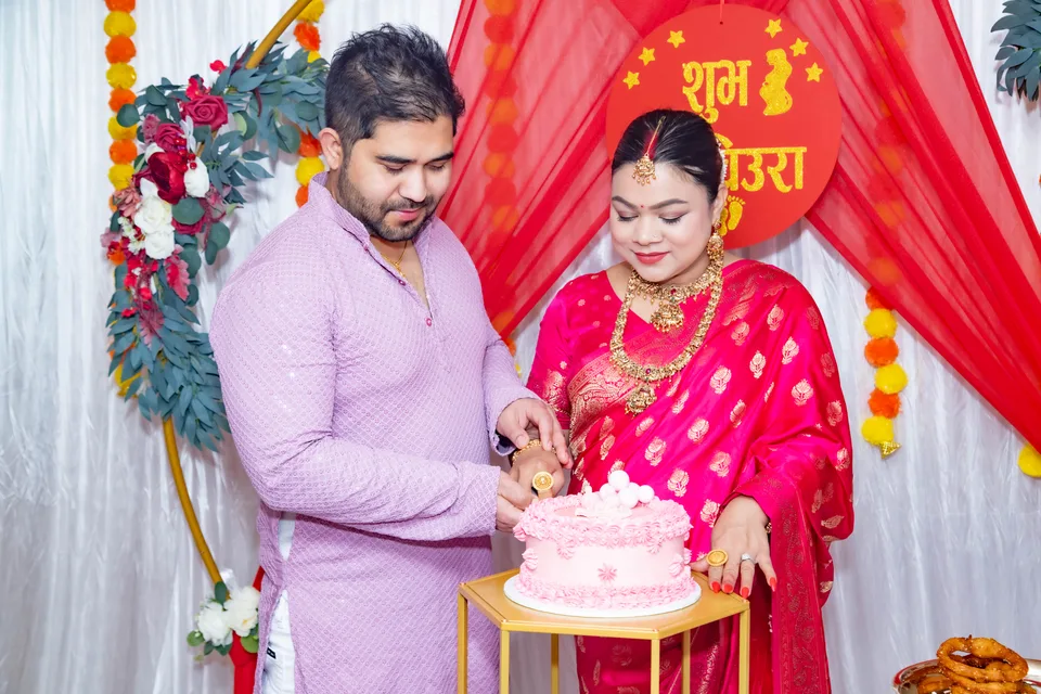 A couple cutting a pink cake at a celebration